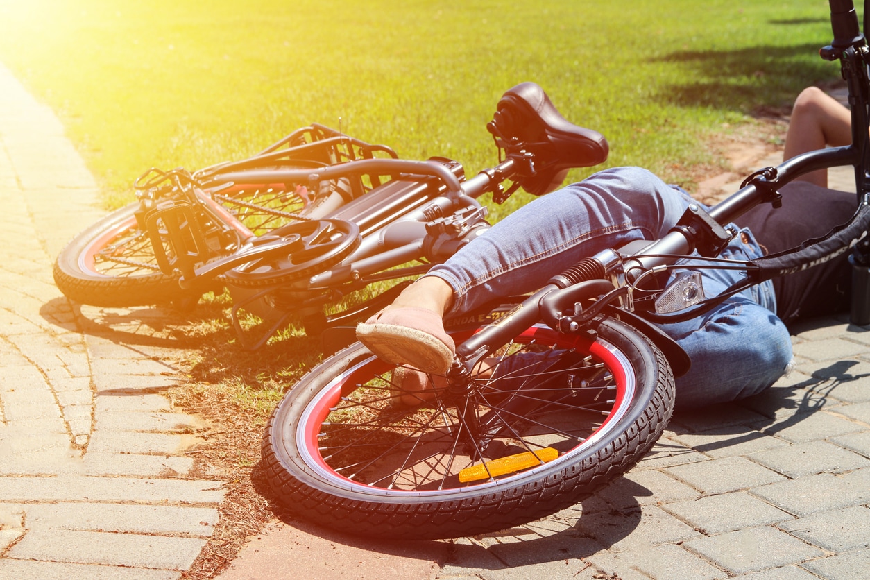 E-bike and teen lying on the ground after accident. SHK Law News